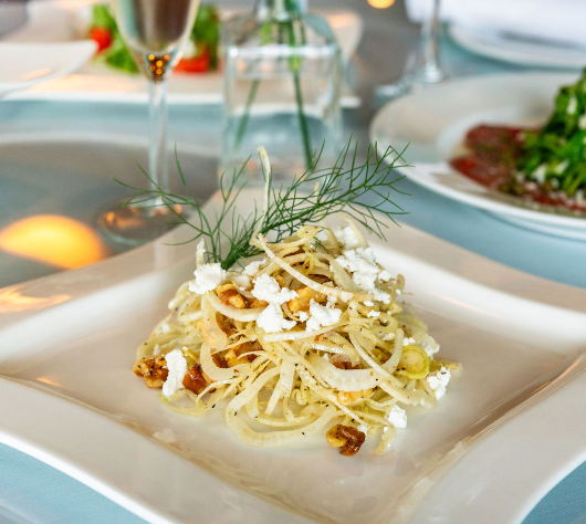 The image is of a plate of pasta, possibly Italian cuisine, served on a table with garnish